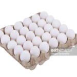 White chicken eggs in a carton tray isolated on white background
